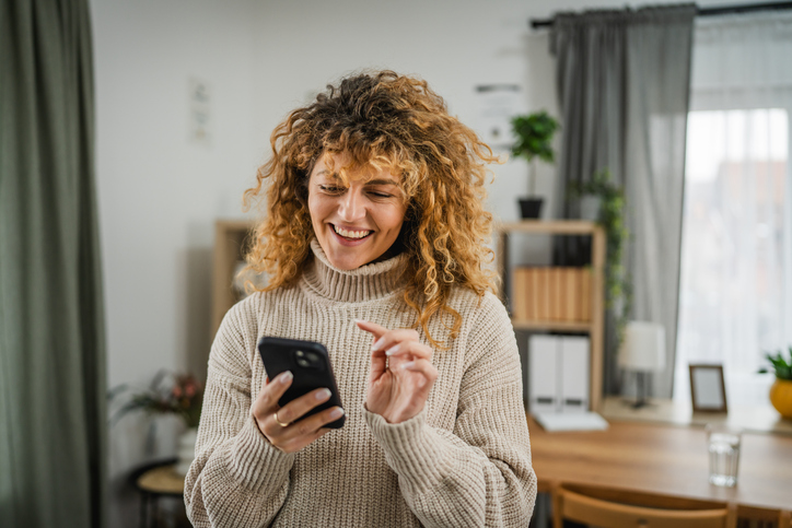 excited adult woman use mobile phone for email at home